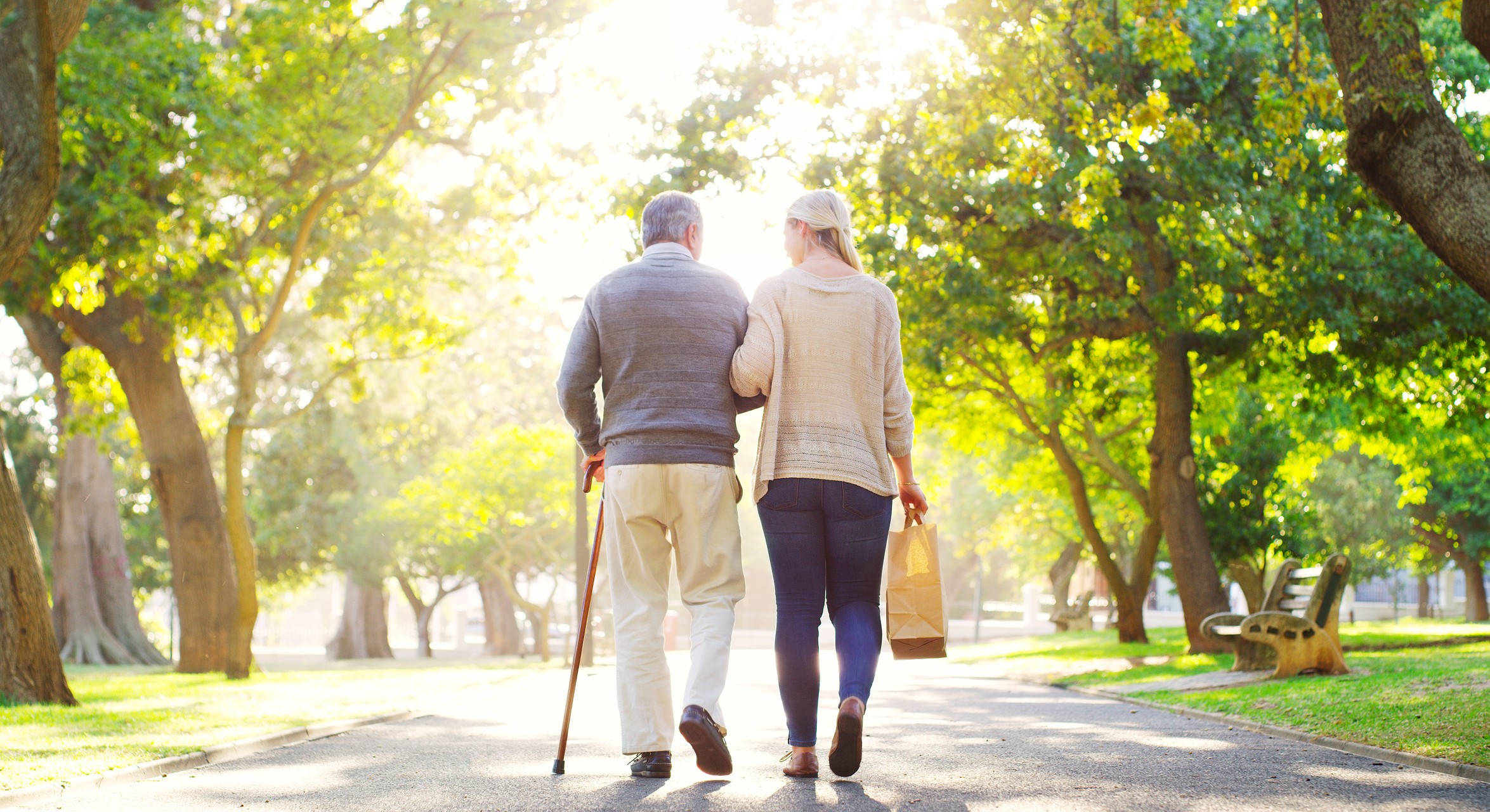 assisting an elderly man walk in the park