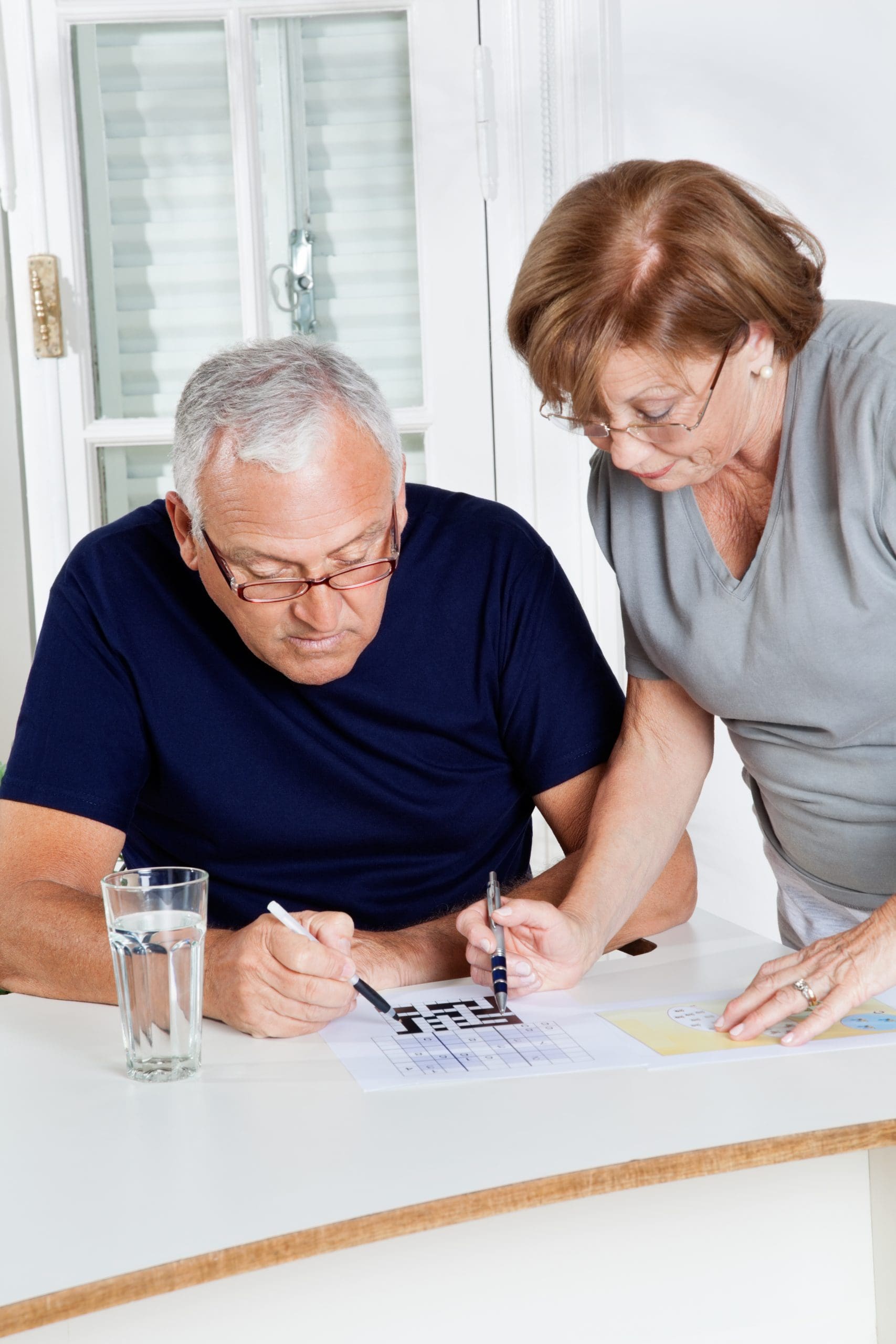 Senior couple doing crossword puzzle together at home to improve their brain health