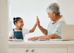 Grandparent helping grandchild with homework, symbolizing the meaningful connections formed through the sandwich generation.