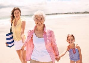 Three generations of a family—grandparent, parent, and child—spending time together, representing the Sandwich Generation experience.