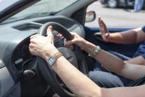 Caregiver stress management showing how to prioritize caregiving tasks by adult daughter driving elderly parent. 