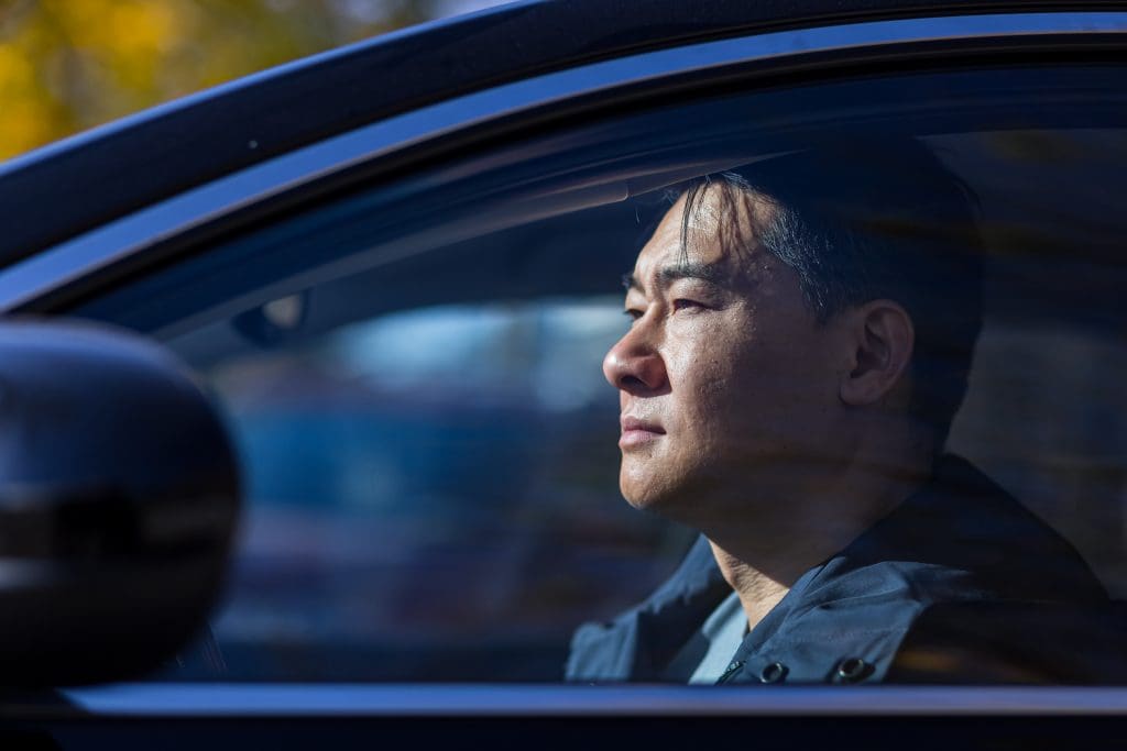 Caregiver burnout is real for caregiver sits in car while facing burnout.