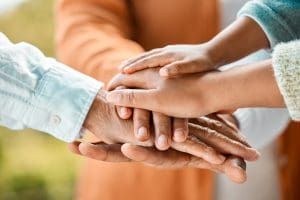 Pile of hands showing unity in sharing the cost of family caregiving.