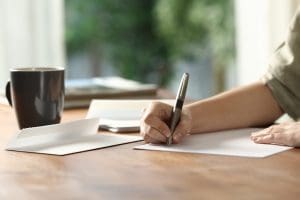 woman-hands-handwriting-letter-on-paper-at-home